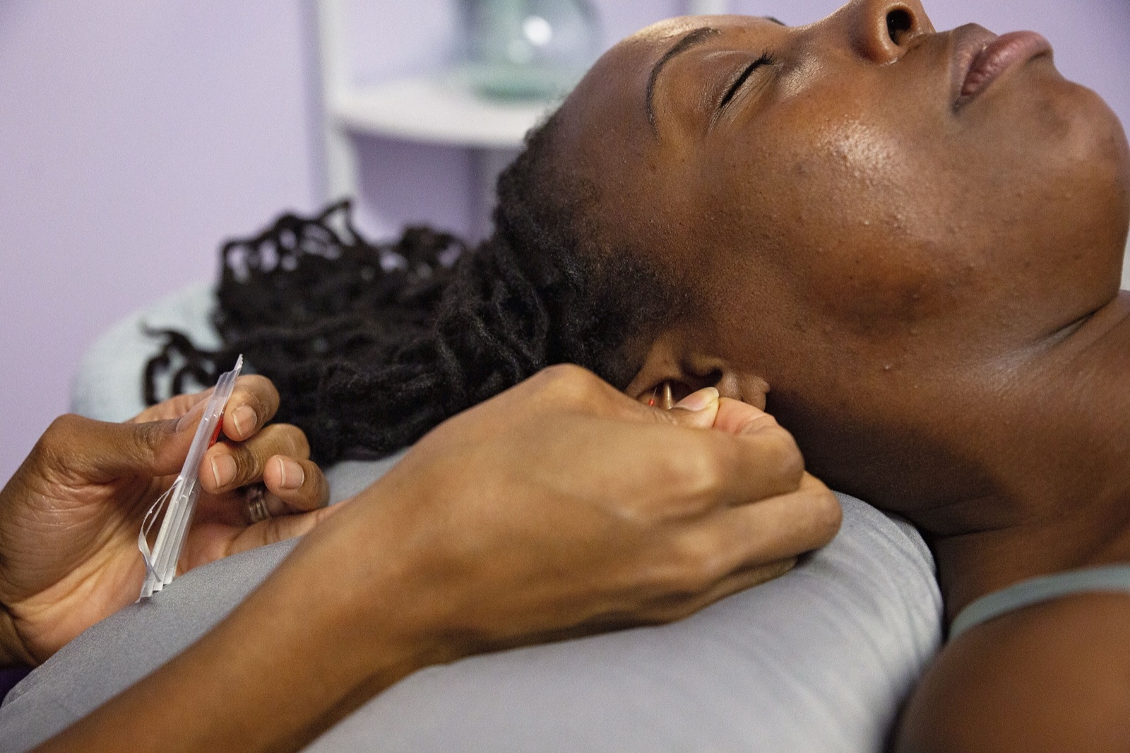 A close view of a fine needle being placed in the ear.